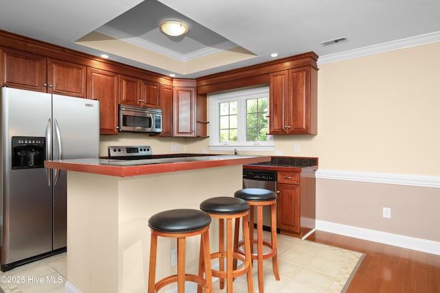143 Rock Creek Dr, New Bern, NC 28562 - kitchen with appliances with stainless steel finishes, ornamental molding, a breakfast bar, a kitchen island, and dark countertops