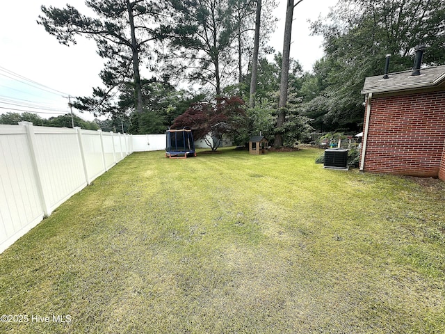 view of yard featuring a trampoline and central AC