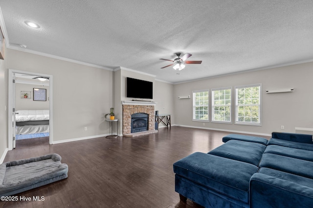living area featuring ceiling fan, a textured ceiling, wood finished floors, a fireplace with raised hearth, and ornamental molding