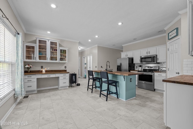 kitchen featuring wooden counters, stainless steel appliances, recessed lighting, a sink, and backsplash
