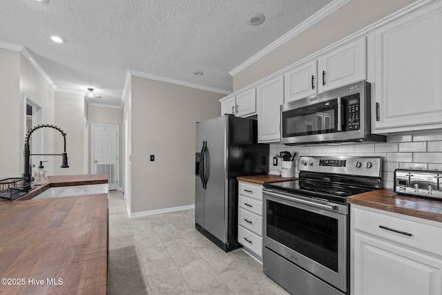 kitchen featuring wooden counters, stainless steel appliances, a sink, white cabinets, and ornamental molding