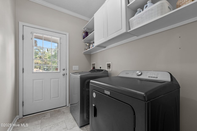 clothes washing area featuring cabinet space, washing machine and dryer, ornamental molding, and baseboards