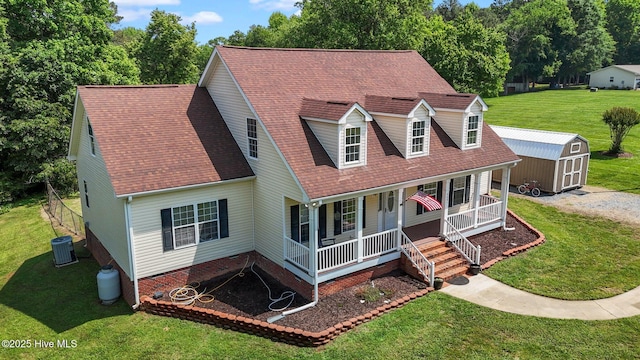 cape cod-style house featuring covered porch, a storage shed, a front yard, an outbuilding, and roof with shingles