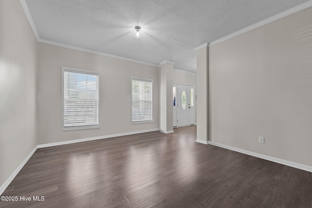 empty room with a textured ceiling, dark wood-type flooring, ornamental molding, and baseboards