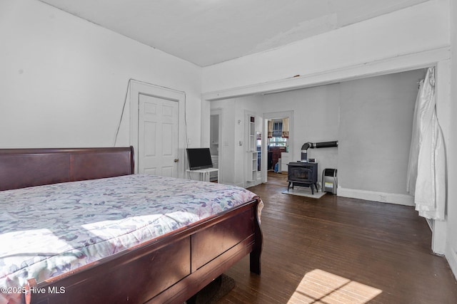 511 Herring Ave NE, Wilson, NC 27893 - bedroom featuring a wood stove, dark wood-style floors, and baseboards