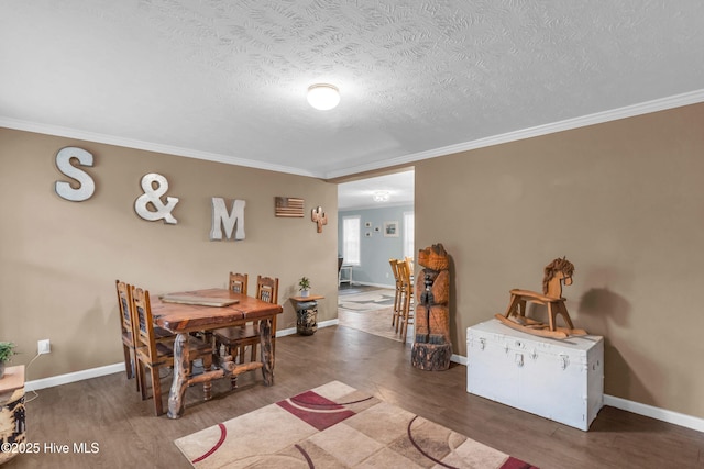 dining area featuring wood finished floors, crown molding, baseboards, and a textured ceiling