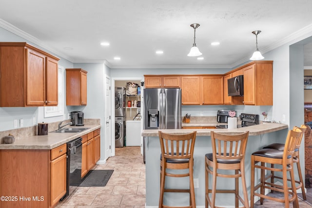 kitchen featuring stainless steel appliances, a sink, stacked washer and clothes dryer, a peninsula, and decorative light fixtures