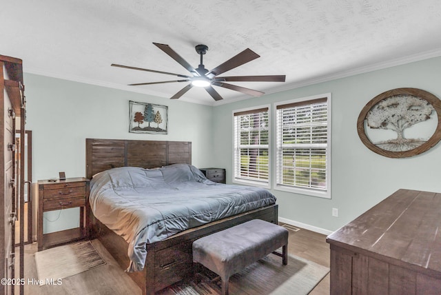 bedroom with wood finished floors, baseboards, ornamental molding, and a ceiling fan