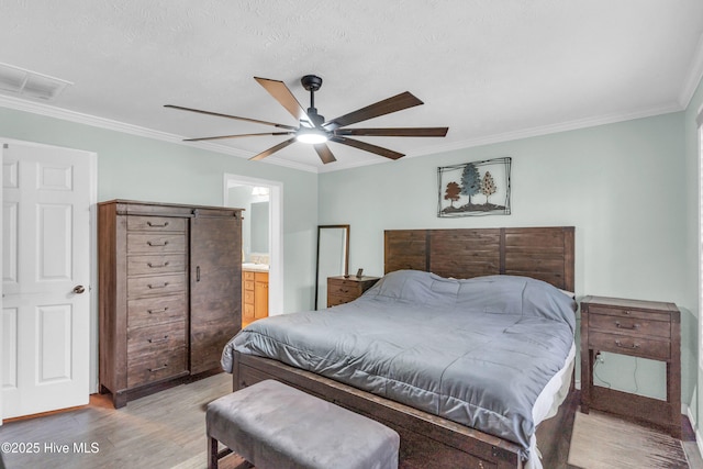 bedroom with light wood-style floors, crown molding, a ceiling fan, and ensuite bath