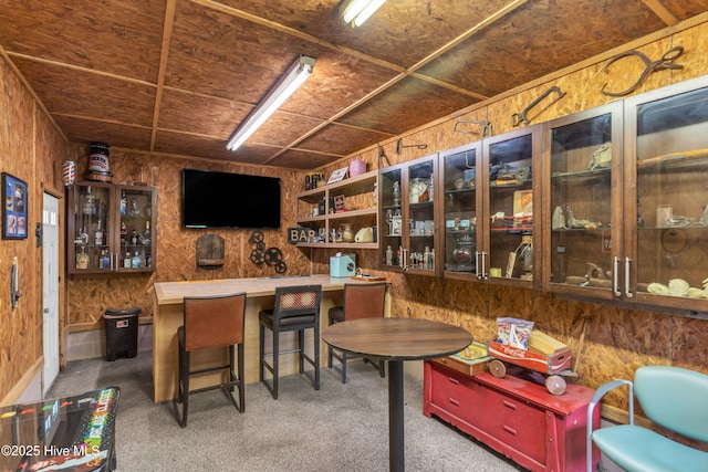 bar featuring carpet flooring and wood walls