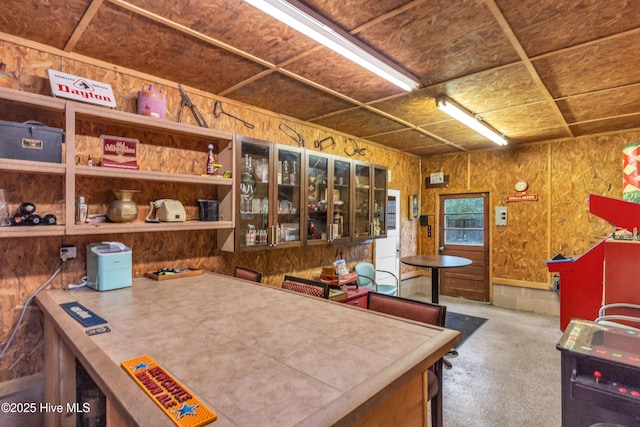 kitchen with carpet, wooden walls, and glass insert cabinets