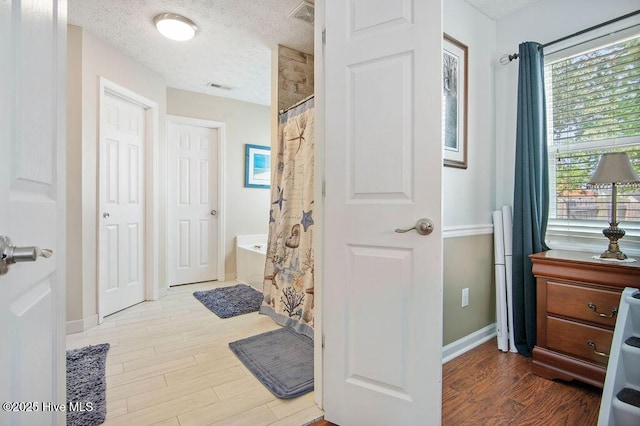 1177 Roberts Rd, Newport, NC 28570 - bathroom with wood finished floors, a shower with shower curtain, a tub to relax in, a textured ceiling, and baseboards