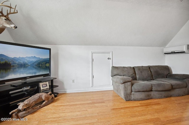 1177 Roberts Rd, Newport, NC 28570 - living area with a wall mounted air conditioner, vaulted ceiling, wood finished floors, baseboards, and a textured ceiling