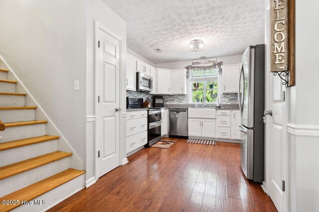 1177 Roberts Rd, Newport, NC 28570 - kitchen featuring stainless steel appliances, white cabinets, dark wood finished floors, decorative backsplash, and a textured ceiling