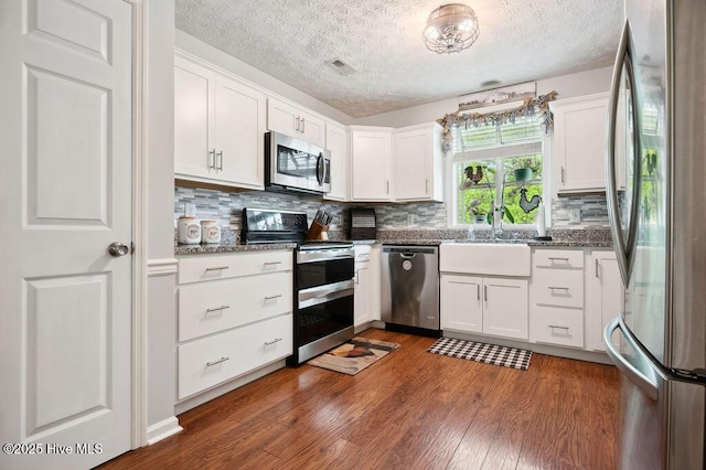 1177 Roberts Rd, Newport, NC 28570 - kitchen with appliances with stainless steel finishes, a sink, dark wood-style floors, white cabinets, and a textured ceiling