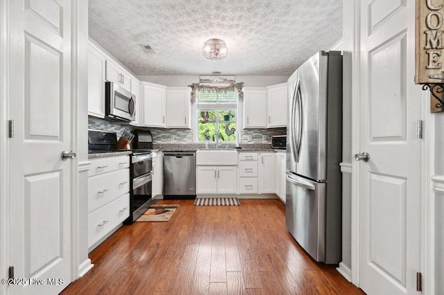 1177 Roberts Rd, Newport, NC 28570 - kitchen featuring stainless steel appliances, white cabinetry, backsplash, dark wood-style floors, and a sink