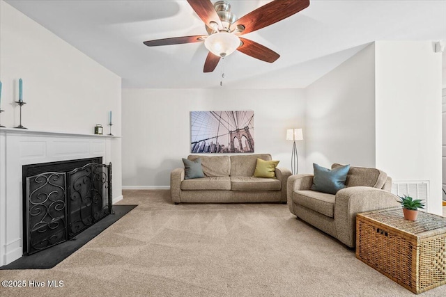 living room with carpet floors, ceiling fan, a fireplace, and baseboards