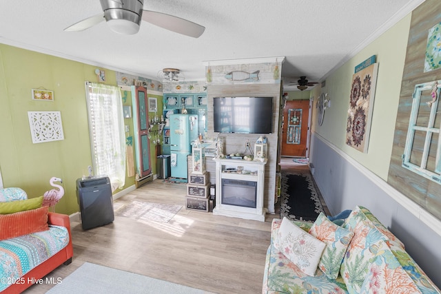 living area featuring a ceiling fan, crown molding, wood finished floors, a textured ceiling, and baseboards