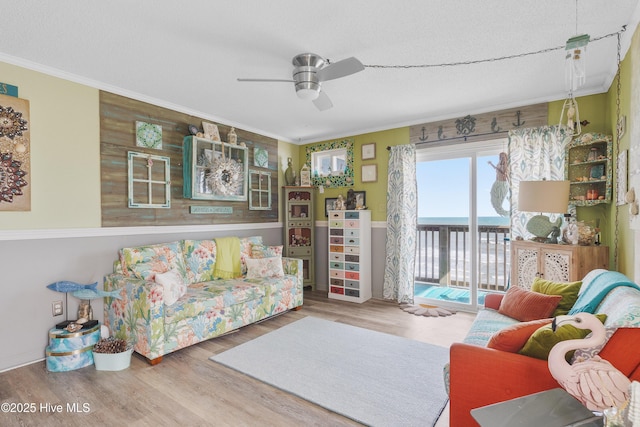 living room with ornamental molding, a ceiling fan, wood finished floors, and a water view