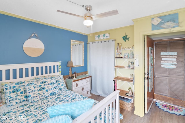 bedroom with wood finished floors, crown molding, and ceiling fan