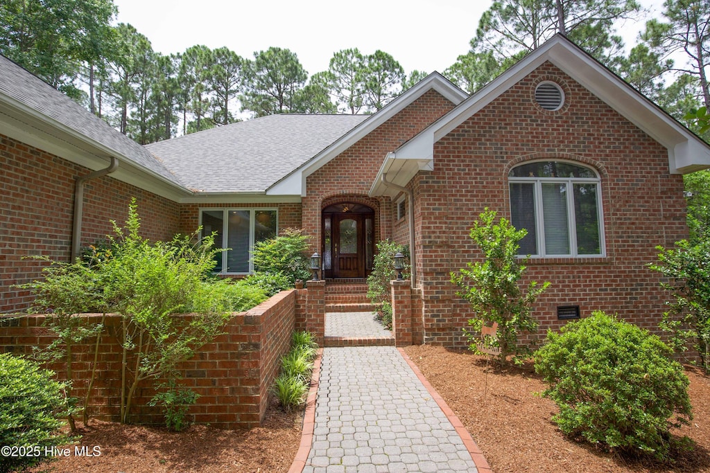 view of front of house featuring brick siding and roof with shingles