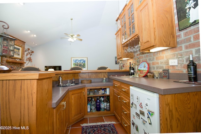 17 Troon Dr, Pinehurst, NC 28374 - kitchen with fridge, lofted ceiling, light tile patterned floors, decorative backsplash, and glass insert cabinets