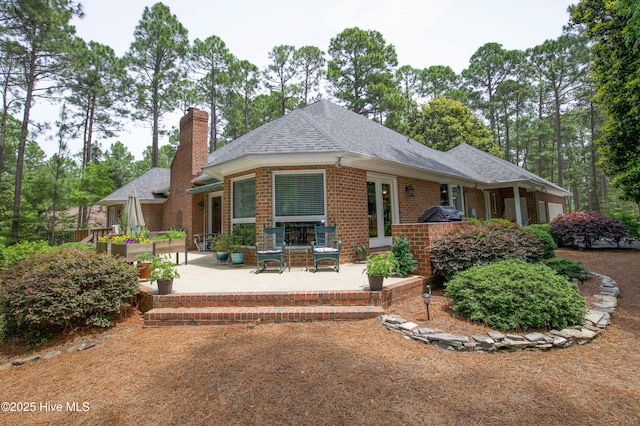 17 Troon Dr, Pinehurst, NC 28374 - view of front of property with a patio, brick siding, roof with shingles, and a chimney