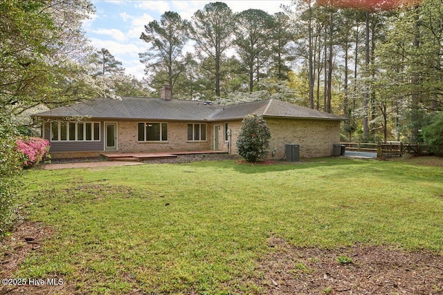 rear view of property with brick siding, a chimney, and central AC unit