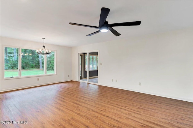 unfurnished room with wood finished floors, a chandelier, a ceiling fan, and baseboards