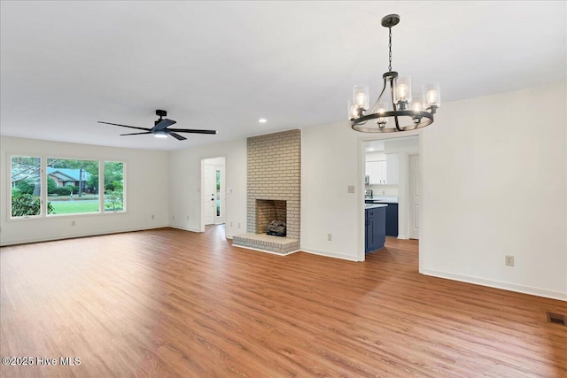 unfurnished living room with light wood finished floors, a chandelier, baseboards, and recessed lighting