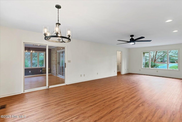 unfurnished room featuring a chandelier, light wood-style flooring, baseboards, ceiling fan, and recessed lighting