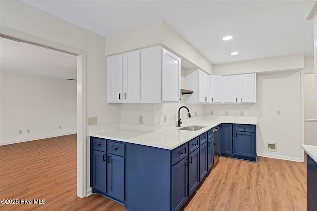 kitchen with a sink, blue cabinets, white cabinets, light wood-style floors, and recessed lighting
