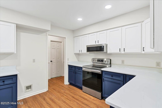 kitchen with appliances with stainless steel finishes, blue cabinets, light wood-style floors, white cabinetry, and light countertops