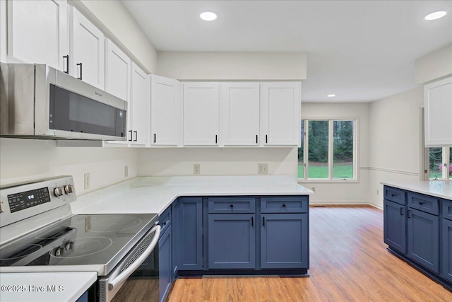 kitchen featuring stainless steel appliances, blue cabinetry, light wood-style flooring, white cabinetry, and recessed lighting
