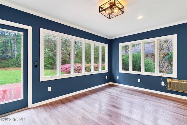 empty room featuring healthy amount of natural light, ornamental molding, wood finished floors, and baseboards