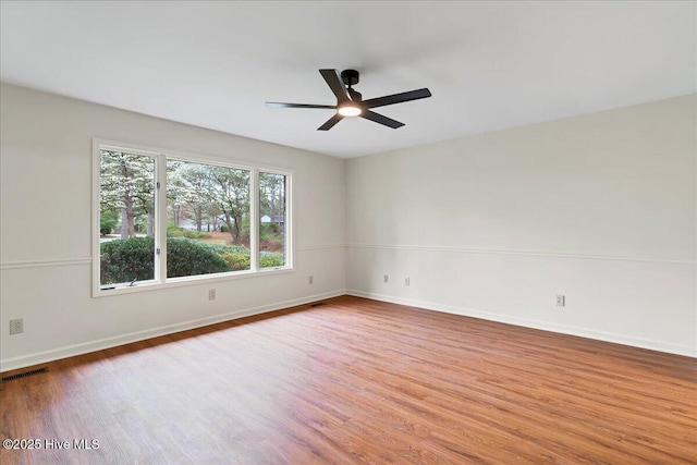 spare room featuring wood finished floors, a ceiling fan, and baseboards