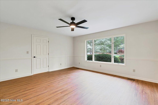 spare room featuring wood finished floors, ceiling fan, and baseboards