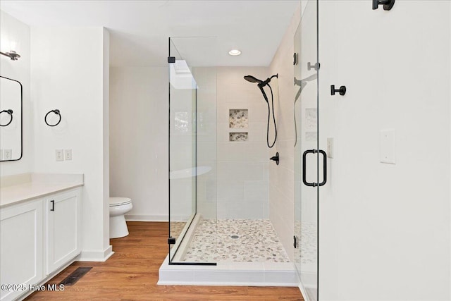 bathroom featuring a shower stall, vanity, wood finished floors, toilet, and recessed lighting