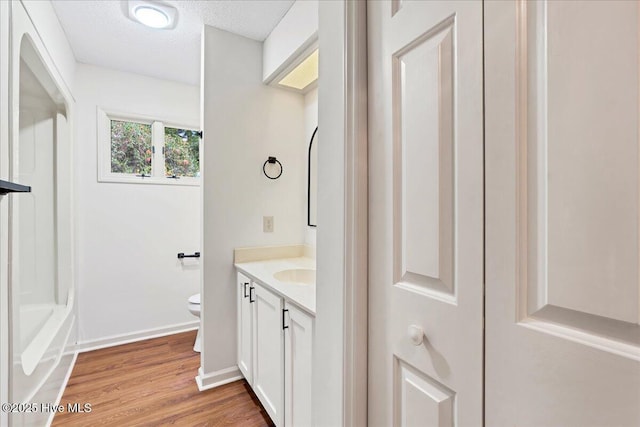 full bathroom featuring vanity, toilet, wood finished floors, baseboards, and a textured ceiling