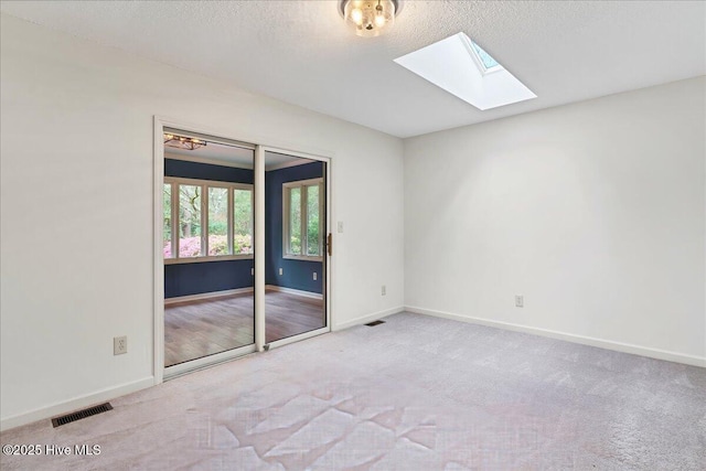 carpeted empty room featuring a skylight, baseboards, and a textured ceiling