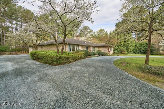 view of front of home with curved driveway, fence, and a chimney