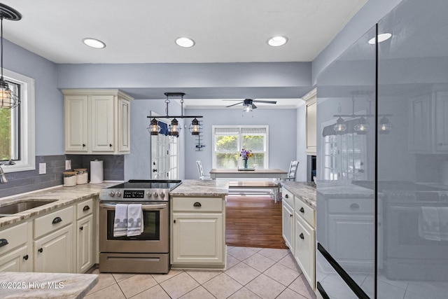 kitchen featuring stainless steel electric stove, light tile patterned flooring, a ceiling fan, a sink, and a peninsula