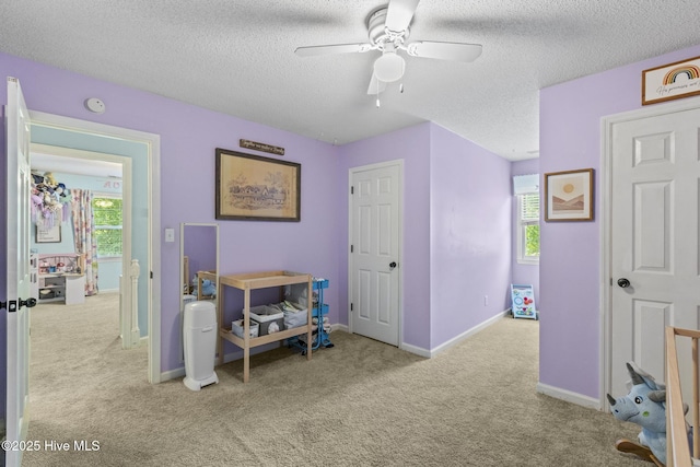 bedroom featuring carpet floors, multiple windows, a textured ceiling, and baseboards