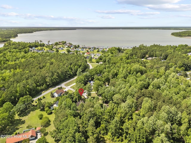 aerial view of property's location featuring a nearby body of water and a heavily wooded area