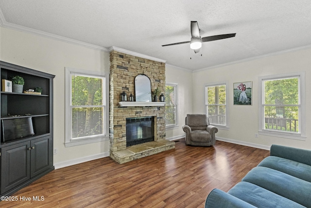 living room with a textured ceiling, wood finished floors, crown molding, a ceiling fan, and a stone fireplace