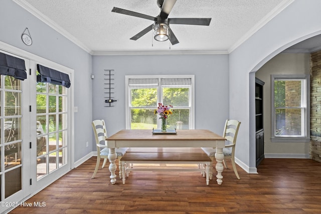 dining space featuring wood finished floors, a textured ceiling, arched walkways, baseboards, and ceiling fan