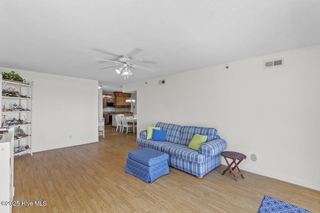 living area with ceiling fan, light wood finished floors, and baseboards