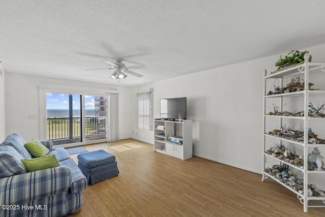 living area featuring wood finished floors, a ceiling fan, and a textured ceiling