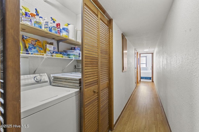washroom with separate washer and dryer, light wood finished floors, a textured wall, baseboards, and a textured ceiling