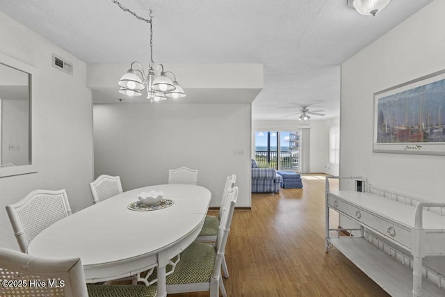 dining space with wood finished floors, a chandelier, and a ceiling fan